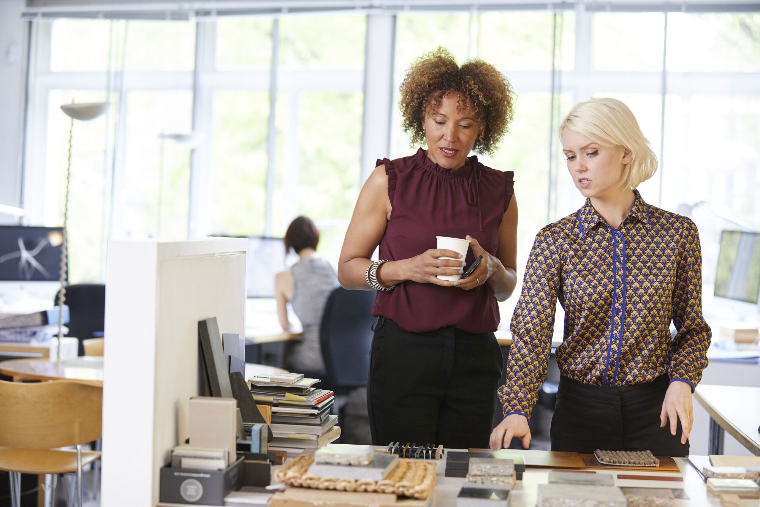 Two female interior designers looking at swatches at office desk